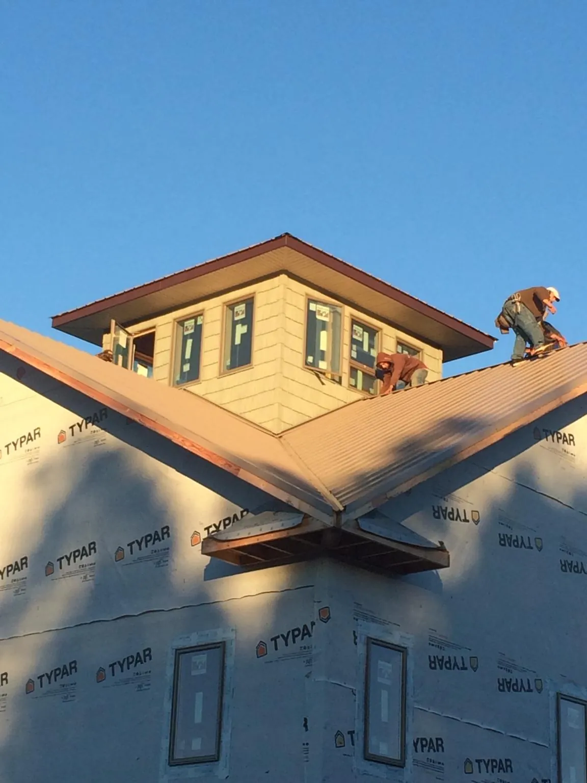 Roofers working around a rooftop cupola on a new metal roof at sunset — Roof Waterproofing in Ogden by Roofing Brothers